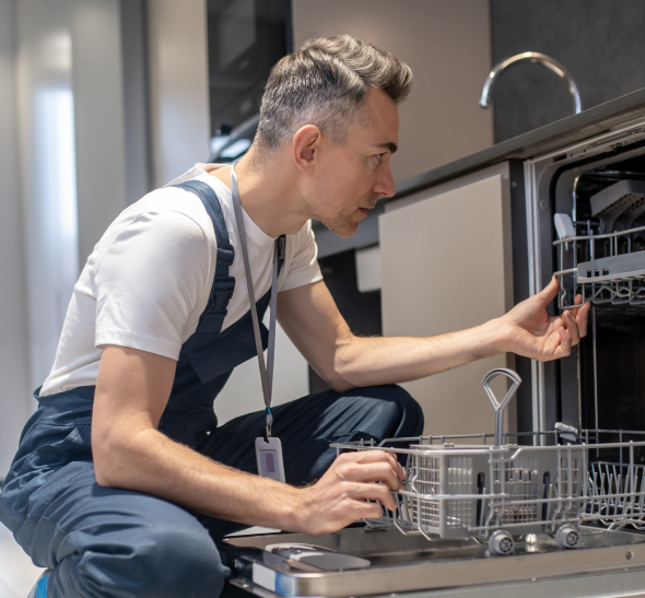 a man in overalls looking at a dishwasher