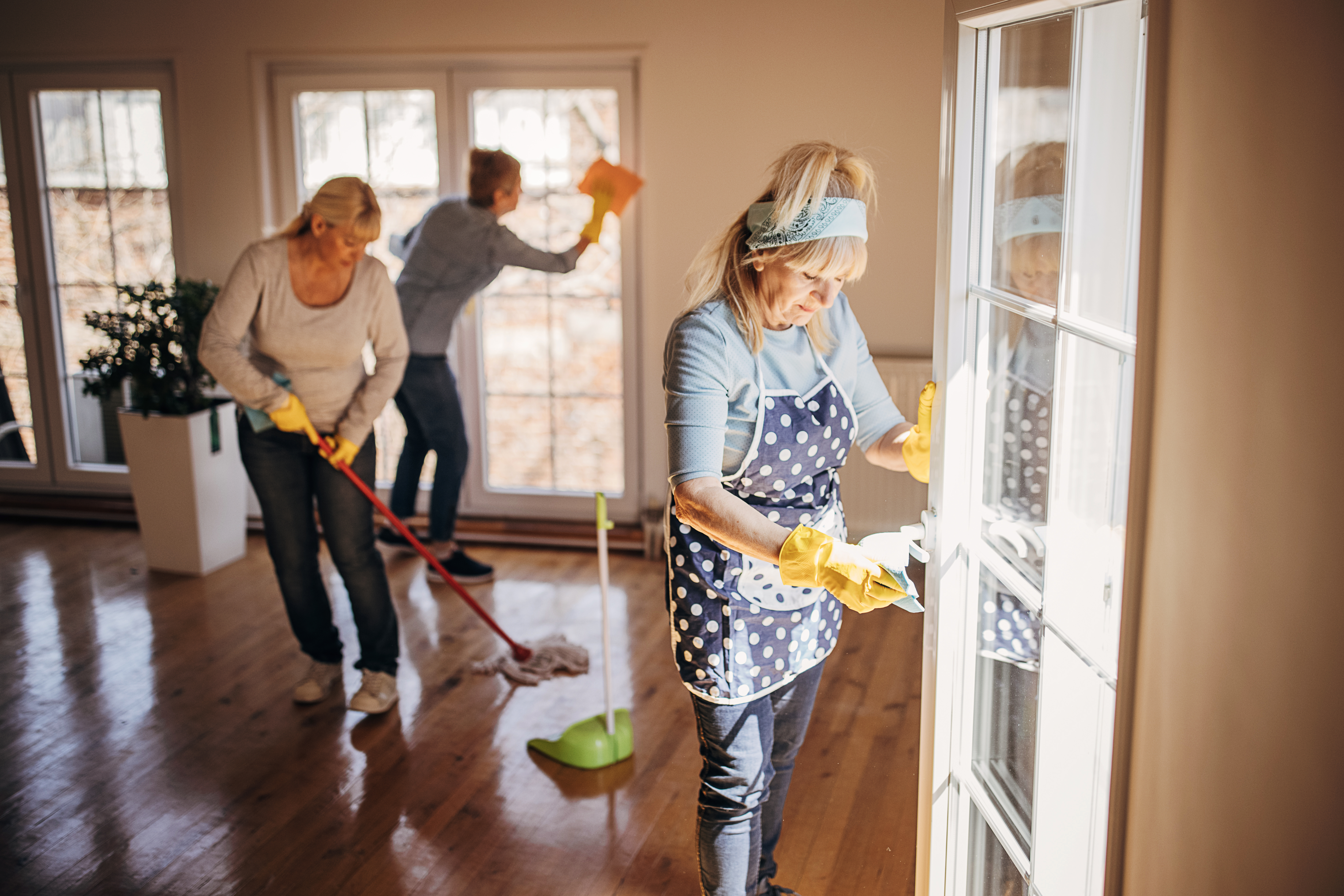 Three women, mature women cleaners from cleaning service, cleaning the apartment together.